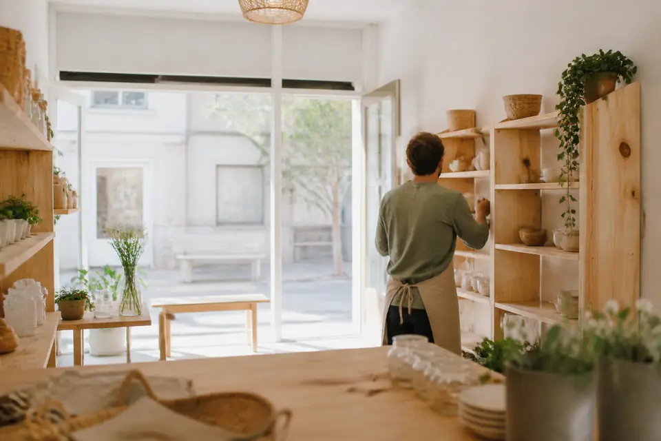 Un commerçant installe sa petite boutique avant l’ouverture, la porte vitrée donne sur la rue