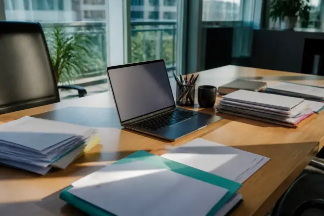 Bureau avec ordinateur portable et dossiers pour comprendre la raison sociale d'une entreprise.