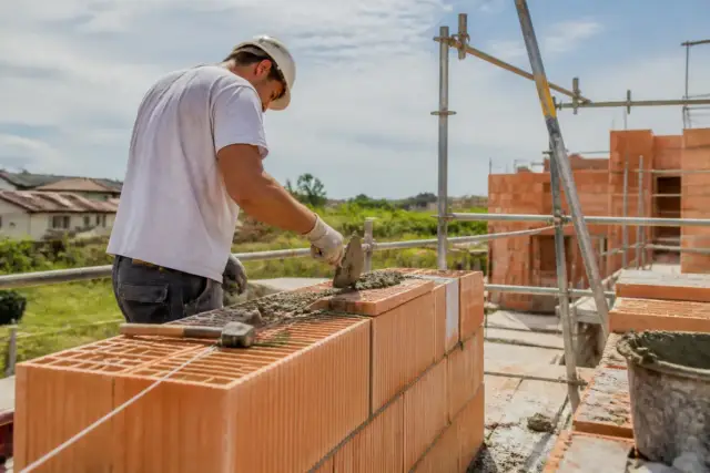 Maçon construisant un mur en briques sur un chantier avec chantierhero.fr tarif compétitif