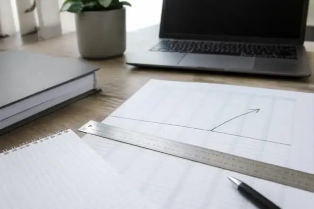 Règle graduée posée sur une feuille de calcul de cotisations, un trait marque le plafond et une flèche pointe les montants au-dessus