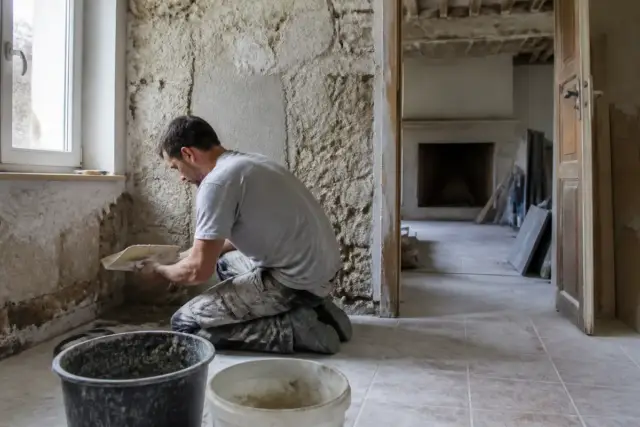 Homme rénovant un mur intérieur, vérification des taux de TVA pour travaux à 10 ou 20