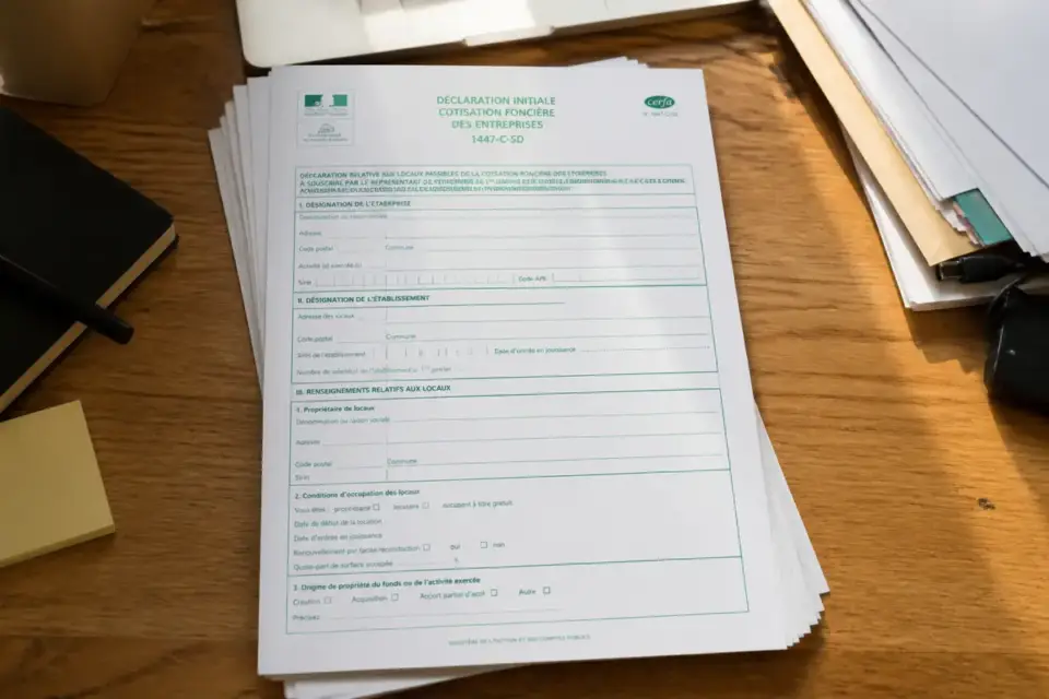 Formulaire de déclaration CFE sur un bureau en bois avec carnet et stylos adjacents
