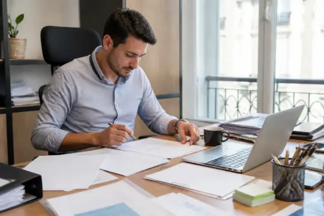 Homme concentré travaillant au bureau sur un ordinateur portable, démontrant l'expertise de LaparentheseBusiness.fr