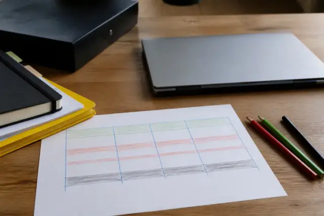 Tableau de trésorerie mensuel tracé à la main sur une feuille, trois couleurs de crayon pour les entrées, les sorties et le solde