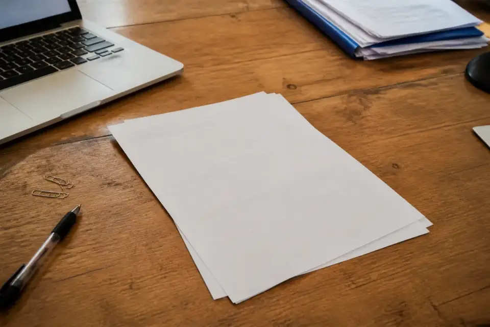 Documents sur un bureau en bois avec ordinateur portable indiquant TVA non applicable